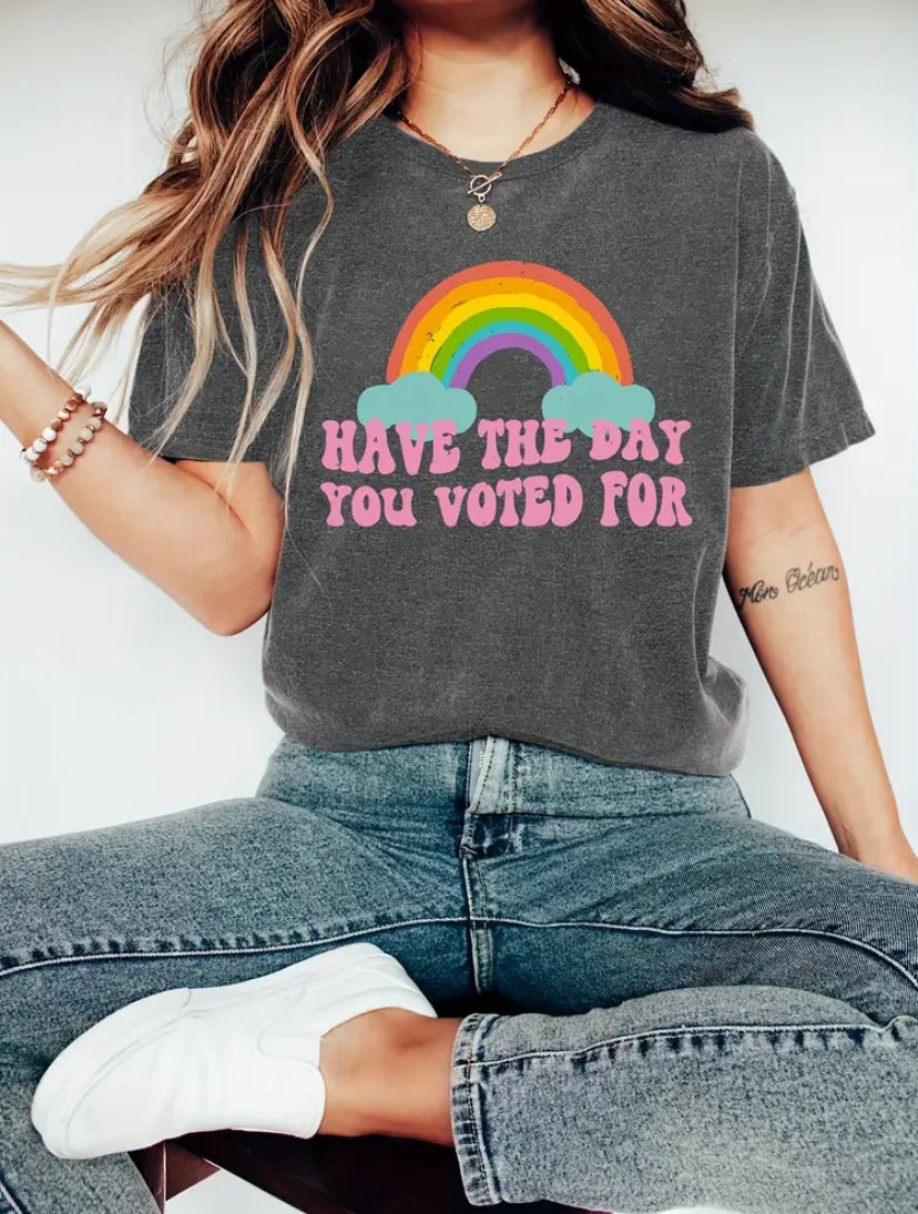 Person wearing a gray t-shirt with a rainbow and text design, sitting on a white background.