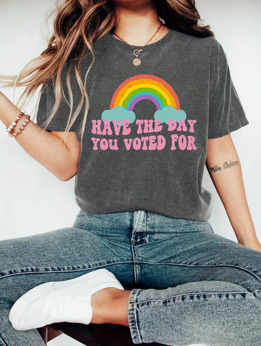 Person wearing a gray t-shirt with a rainbow and text design, sitting on a white background.